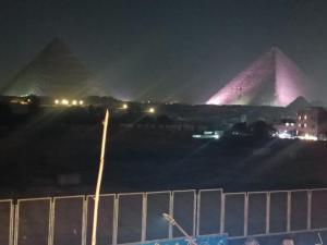 a view of two pyramids at night with lights at Sneferu hotel pyramids View in Cairo