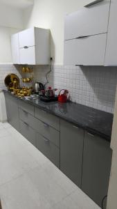 a kitchen with white cabinets and a black counter top at The Aura stays in Indore