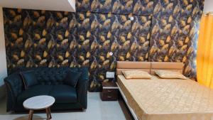 a bedroom with a bed and a couch and a wall at The Aura stays in Indore +3 photos