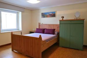 a bedroom with a wooden bed with purple pillows and a window at La Casona de Ilusión in Solórzano