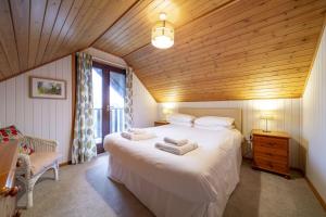 a bedroom with a large white bed with a wooden ceiling at E42 - Nare in Truro +20 photos
