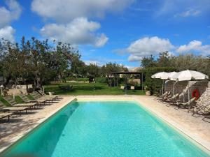 a swimming pool with chairs and an umbrella at Masseria Cianciò in Casa Serrafiori