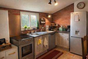 a kitchen with a stove and a sink and a refrigerator at LE PETIT CHALET DE SYLVIANE in Budelière