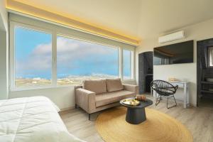 a bedroom with a bed and a chair and a large window at Sweet nectar villa at Pyrgos with heated jacuzzi in Pyrgos