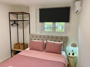 a bedroom with a pink bed and a window at Nikol's central suite 1 in Nea Peramos