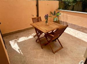 a wooden table and chairs with flowers on a patio at Fiorucci Apartments - Daniele's House Lago Di Bolsena in Marta
