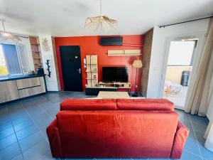 a living room with a red couch and a television at L'Escale paisible in Gardanne