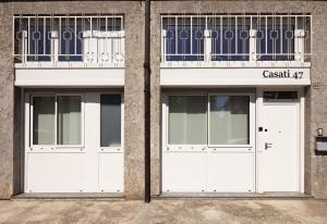 due porte da garage bianche sul lato di un edificio di Casati47 a Magenta
