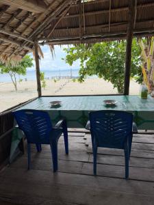 a table and chairs on a porch with the beach at West Waigeo Bungalow in Kabu +90 photos