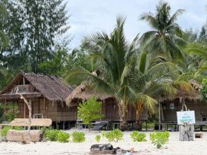 a resort with two palm trees and a building at West Waigeo Bungalow in Kabu