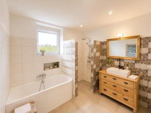 a bathroom with a tub and a sink and a mirror at Finca Ludwig am Forggensee in Rieden