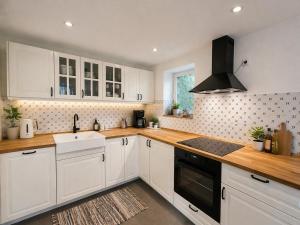 a kitchen with white cabinets and a sink and a stove at Finca Ludwig am Forggensee in Rieden +2 photos