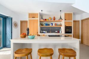 a kitchen with wooden cabinets and a counter with stools at Ikos Kythnos in Kithnos +28 photos