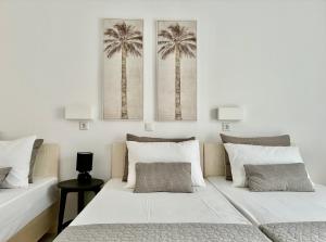 two beds in a bedroom with palm trees on the wall at Thalassa Garden Studios in Pefkochori