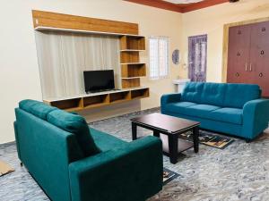 a living room with two blue couches and a table at A2KD Stay - Achyutam Keshavam Krishna Damodaram in Tiruvannāmalai