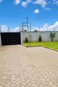 a brick parking lot with a fence and grass at Kisii cottage in Kisii