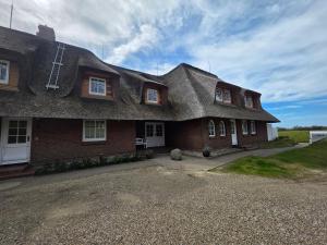 a large brick house with a thatched roof at Westerhuk App 3 in Keitum
