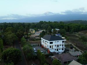 an aerial view of a white building with a mountain in the background at Kiliscape Hotel Moshi in Uru
