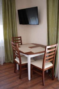 a table and chairs with a television on a wall at Sódomb vendégház in Egerszalók