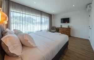 a bedroom with a large white bed and a large window at Chez Nous I e II in Caloura