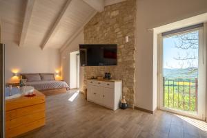 a bedroom with a bed and a tv on a stone wall at Valle in Fiore Suite - Private Jacuzzi & Sauna - ItalyWeGo in Ilci