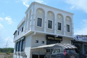 a white building with a car parked in front of it at Hotel Griffin in Kīratpur
