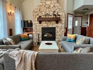 a living room with two couches and a stone fireplace at Spa & Pool Table - L Experience in Petite-Rivière-Saint-François