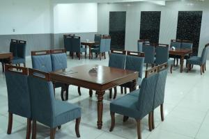 a dining room with wooden tables and blue chairs at Hotel Griffin in Kīratpur