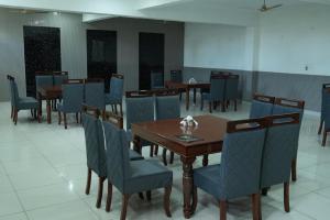 a dining room with wooden tables and blue chairs at Hotel Griffin in Kīratpur