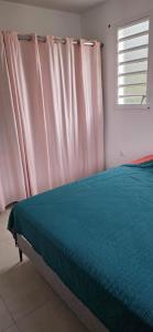 a bed in a room with a window and a bedskirtspectspectspectspects at Anse a l ane in Les Trois-Îlets +2 photos