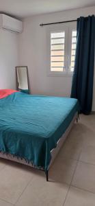 a bedroom with a bed with a blue comforter and a window at Anse a l ane in Les Trois-Îlets