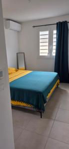 a bedroom with a bed with a yellow and blue blanket at Anse a l ane in Les Trois-Îlets