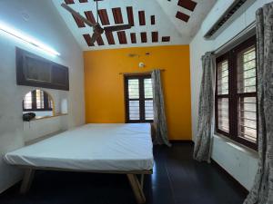a bedroom with a bed and a yellow wall at Gravity Groups SSK - Near Sangamithra Jipmer in Puducherry Airpoert