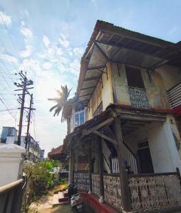 a building with a balcony and a palm tree at Vikram homestay in Malvan