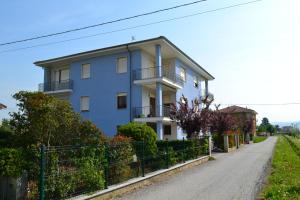 a white house on a road with a fence at Alloggio per 4 persone con due camere da letto e cucina in Carrù