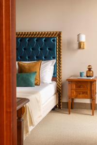 a bedroom with a bed with a blue headboard and a table at Sarzana Park Hotel in Sarzana