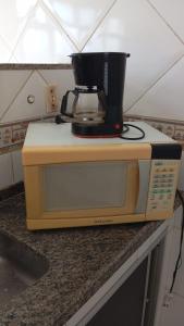 a coffee pot on top of a microwave on a counter at Suite Brisa 201 in Pedra de Guaratiba