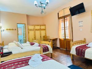a hotel room with three beds and a television at Hostal La Posada De La Abuela in La Paz