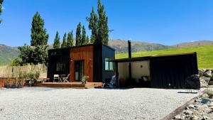 a black house with a green roof on a gravel yard at Grace & Rose in Gibbston