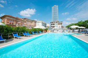 a swimming pool with blue chairs and a building at Hotel Stefania in Cesenatico