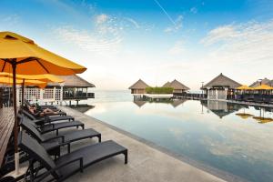 Avani Sepang Goldcoast Resort في سيبانغ: وجود مسبح في المنتجع مع الكراسي والمظلات