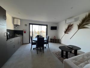a kitchen and a living room with a table and chairs at Les Appartements chez Hanene in Le Grau-du-Roi +4 photos