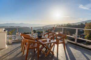a patio with a table and chairs on a balcony at Kaafal Cottage in Mukteshwar