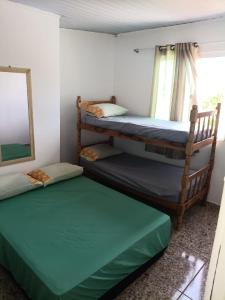 two bunk beds in a room with a window at Casa 70 Hostel 350m da praia Balneario Flamingo in Matinhos
