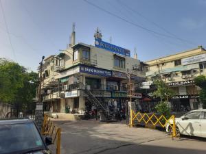 ein Gebäude an einer Straße, vor dem Autos parken in der Unterkunft Hotel Pine Ville in Ahmedabad