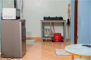 a kitchen with a refrigerator and a table with a red appliance at Reenhomes in Kilifi +3 photos