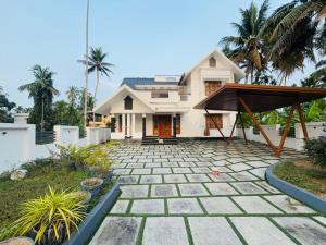 a house with a stone patio in front of it at THE iVORY VILLA in Kottayam