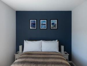 a blue bedroom with a bed with three pictures on the wall at Sunny Ridge in Fort Augustus
