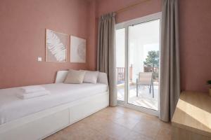 a bedroom with a white bed and a balcony at Sunset Cove by halu! - Spacious 4-bedroom Villa in Neos Marmaras