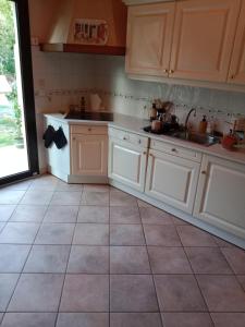 a kitchen with white cabinets and a tile floor at Maison au bord de l'Erdre in La Chapelle-sur-Erdre +3 photos